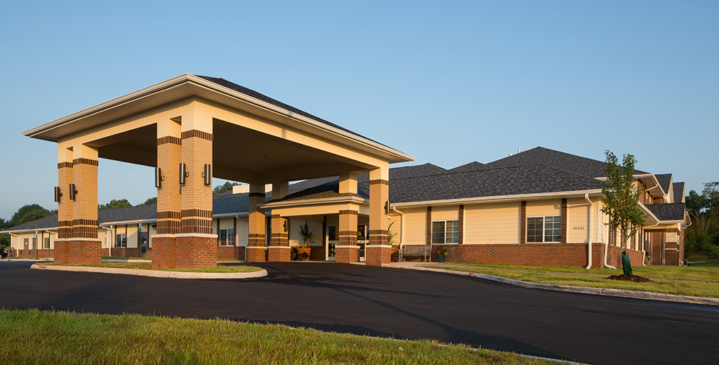 Exterior shot of a yellow and brick building and driveway
