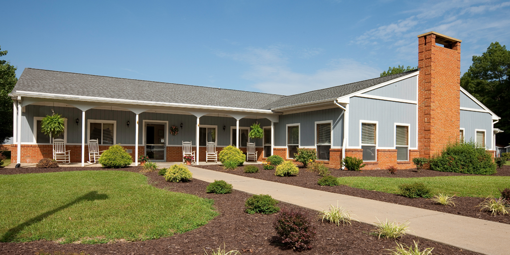 Exterior shot of a blue siding and brick building with a rocking-chair lined porch