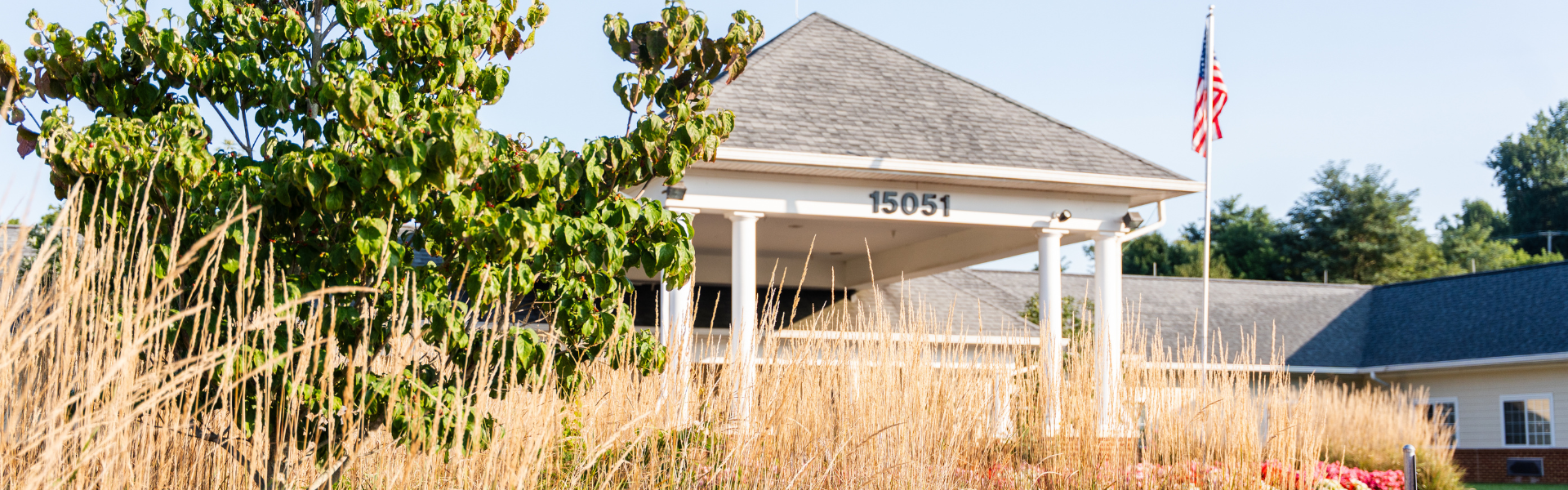 Exterior photo of the Abingdon Health & Rehab Center covered entryway, numbered 15051 and shot through foliage